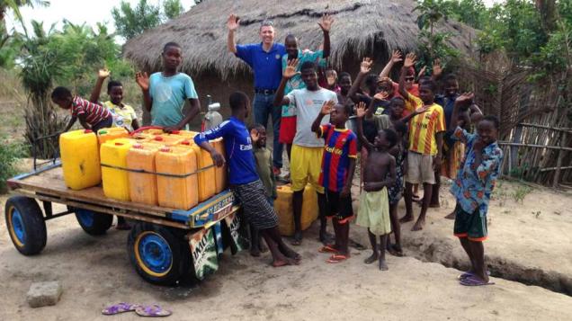  Los rotarios Craig Sorensen y Marty Hatala junto a residentes de la aldea de Adevukope y los recipientes con el primer suministro de agua pura que llega a la comunidad.  Fotografía de: Cortesía de Craig Sorensen